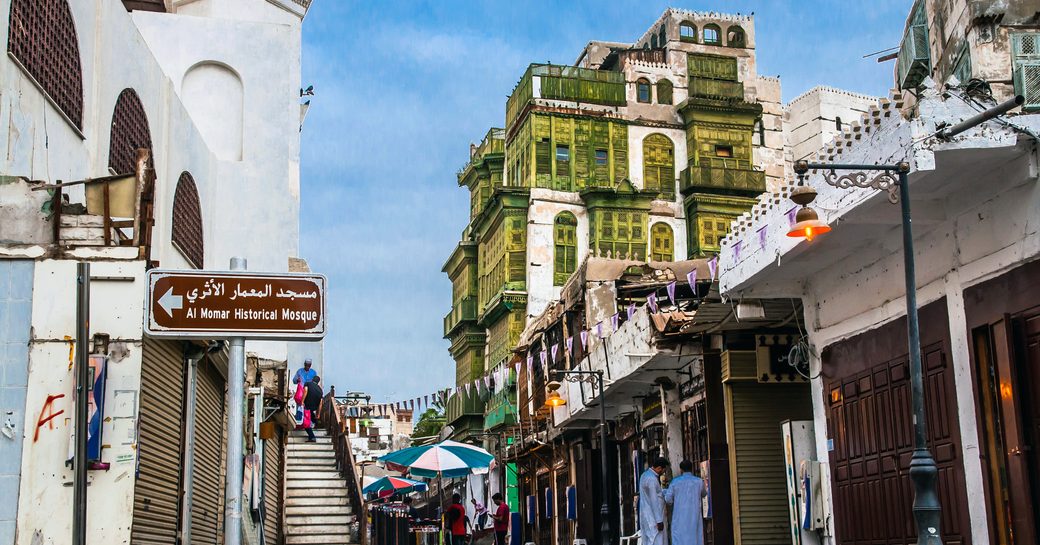 World heritage site of Jeddah city-center, buildings to both sides of frame with older buildings in background.