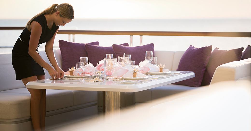 a superyacht crew member preparing a table with pink decor 