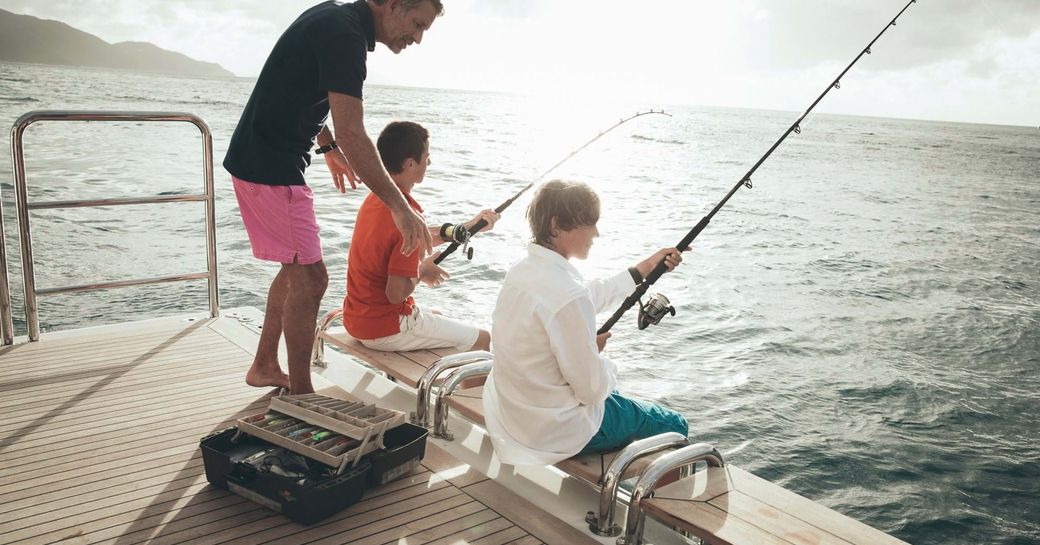 family fishing on a secluded cove in the Mediterranean away from high risk zones of coronavirus while on their luxury yacht vacation 