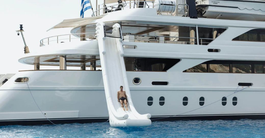 A water slide attached to charter yacht EMIR, with a male charter guest sliding down