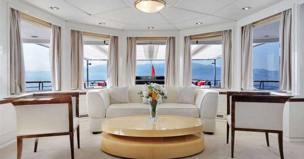 cream sofas, dainty chairs and wide windows in lounge room of luxury yacht