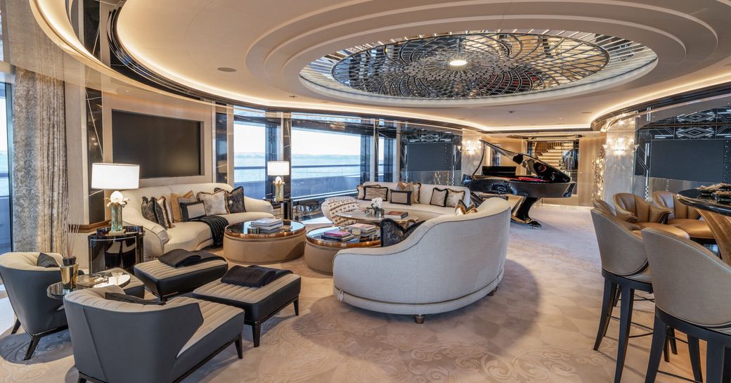 Interior lounge area onboard superyacht charter KISMET with wet bar to starboard and a grand piano aft