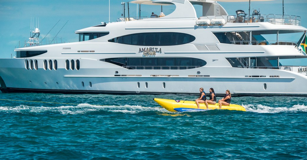 superyacht ‘Amarula Sun’ anchored in the Bahamas as charter guests play on the banana boat