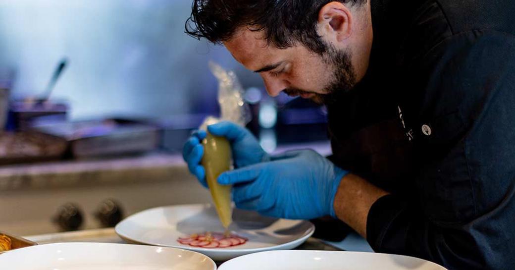 A superyacht chef plating up food during a competition