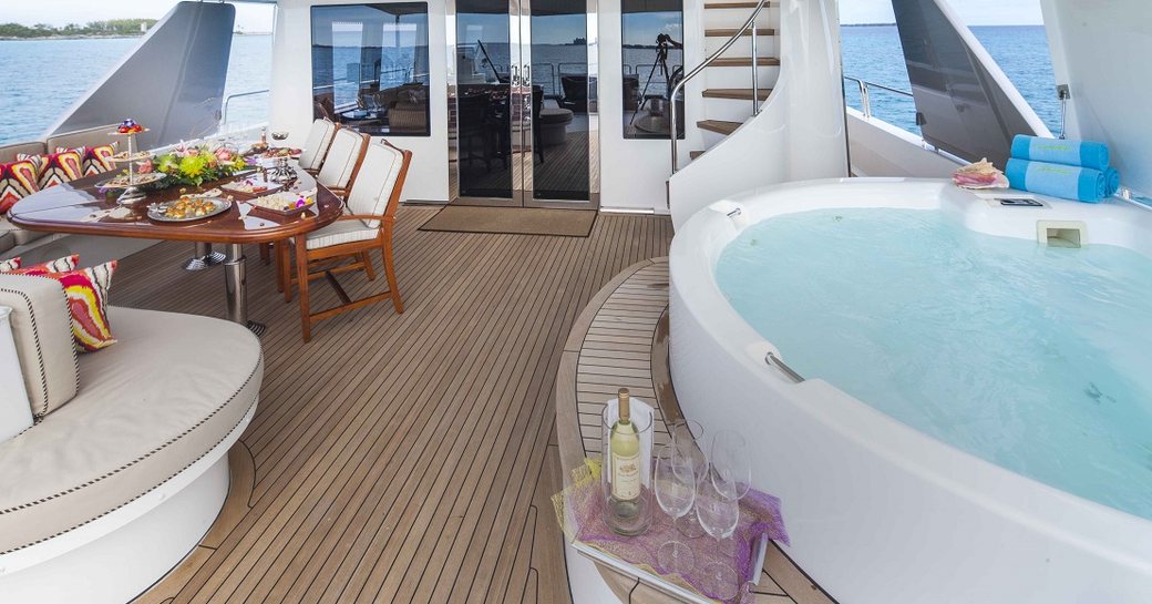 Upper deck of superyacht AMITIE, with spa pool in foreground and al fresco dining area