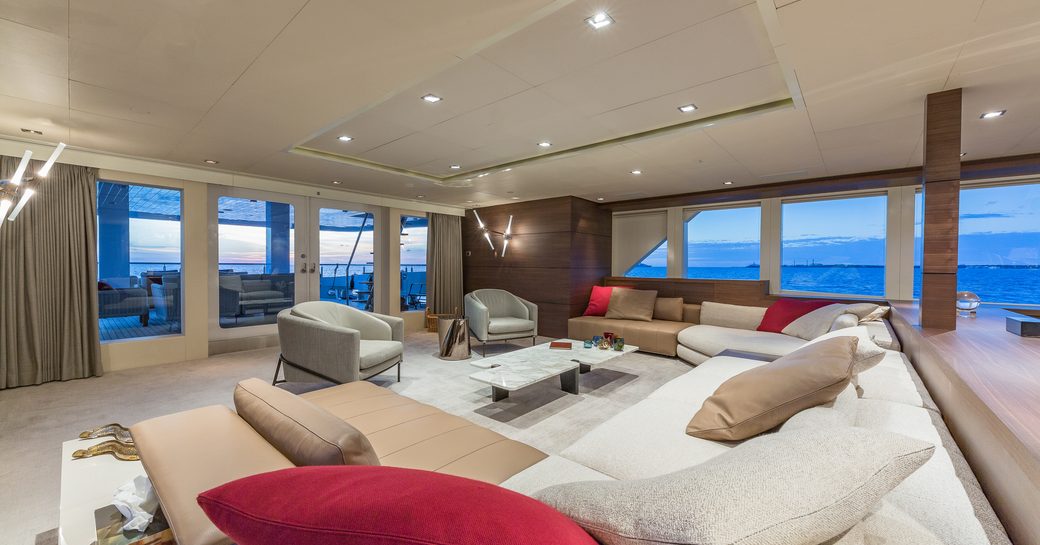 Main salon onboard charter yacht BIG SKY, spacious lounge area with sofas and armchairs, surrounded by full height windows