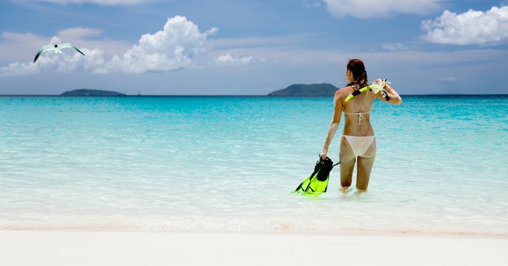 female charter guests snorkels in clear waters of the Caribbean while on a luxury yacht charter