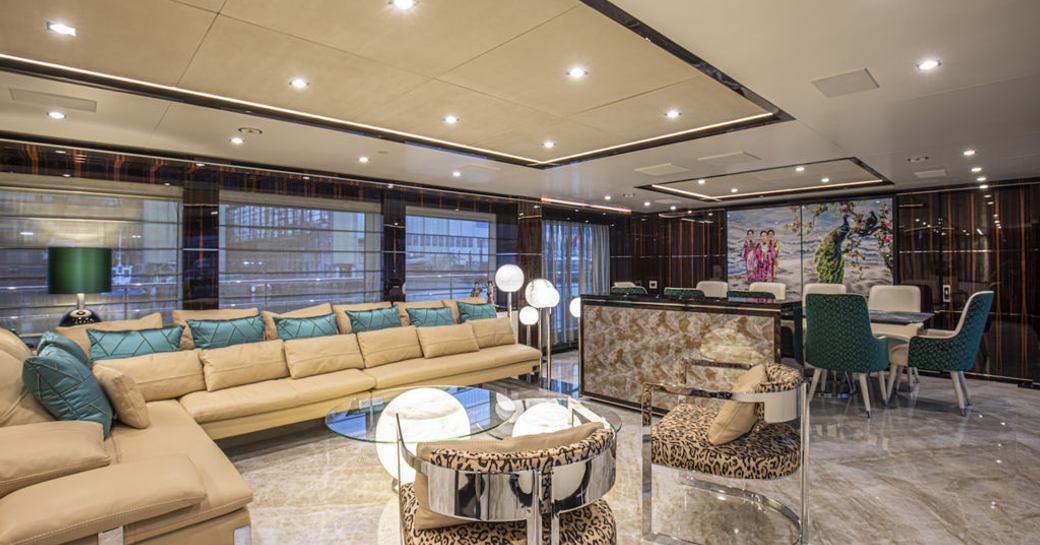 Main salon onboard charter yacht HAPPY ME, L-shaped cream seating with a dining area aft