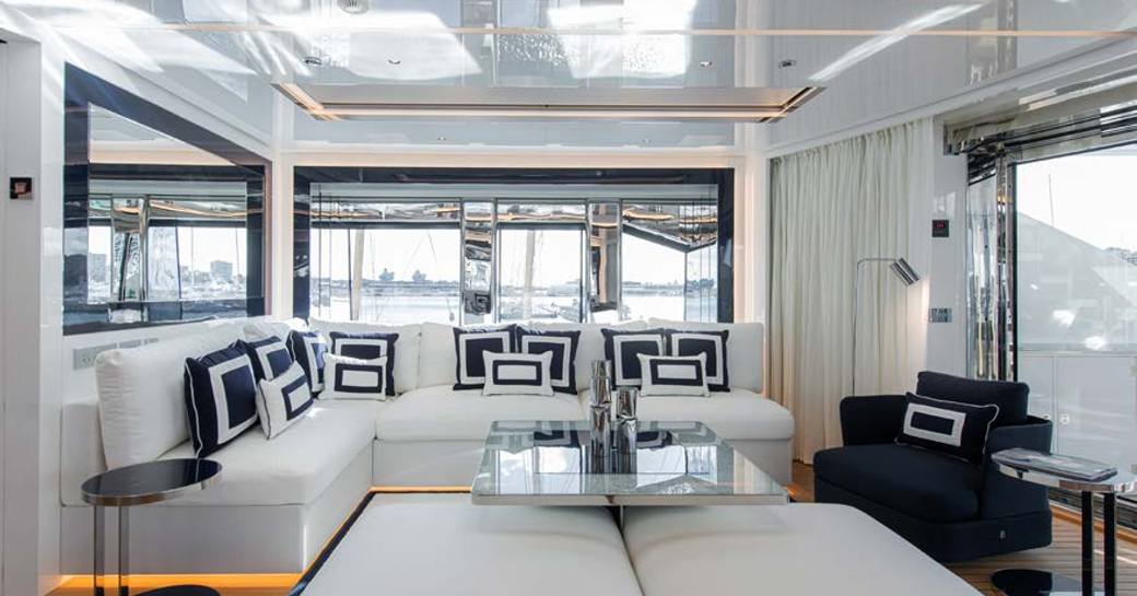 Lounge area on the main deck onboard charter yacht RESILIENCE, pluish white seating surrounded by full height windows
