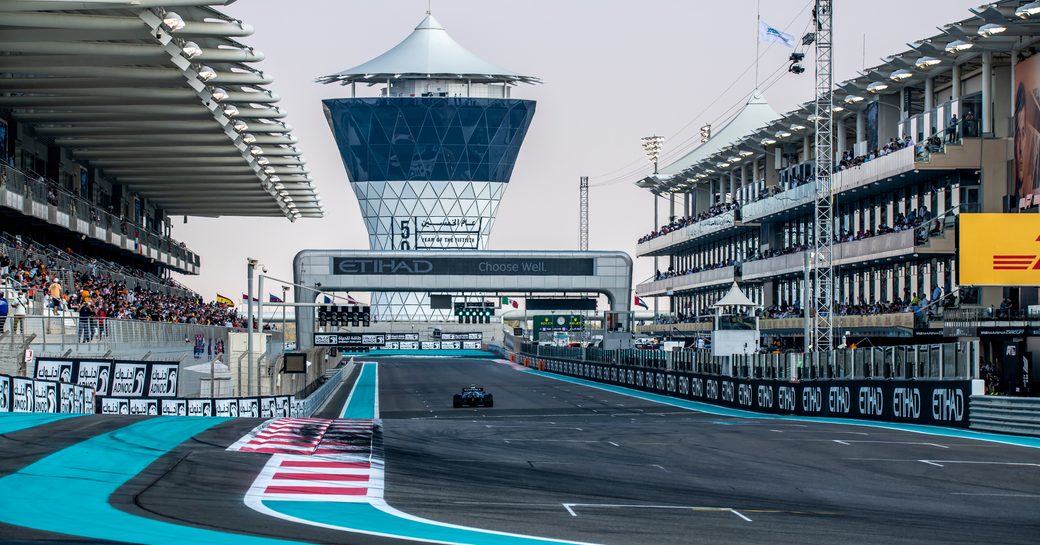 Yas Marina Circuit in Abu Dhabi during Abu Dhabi Grand Prix. Spectators in stands and solo car on approach.