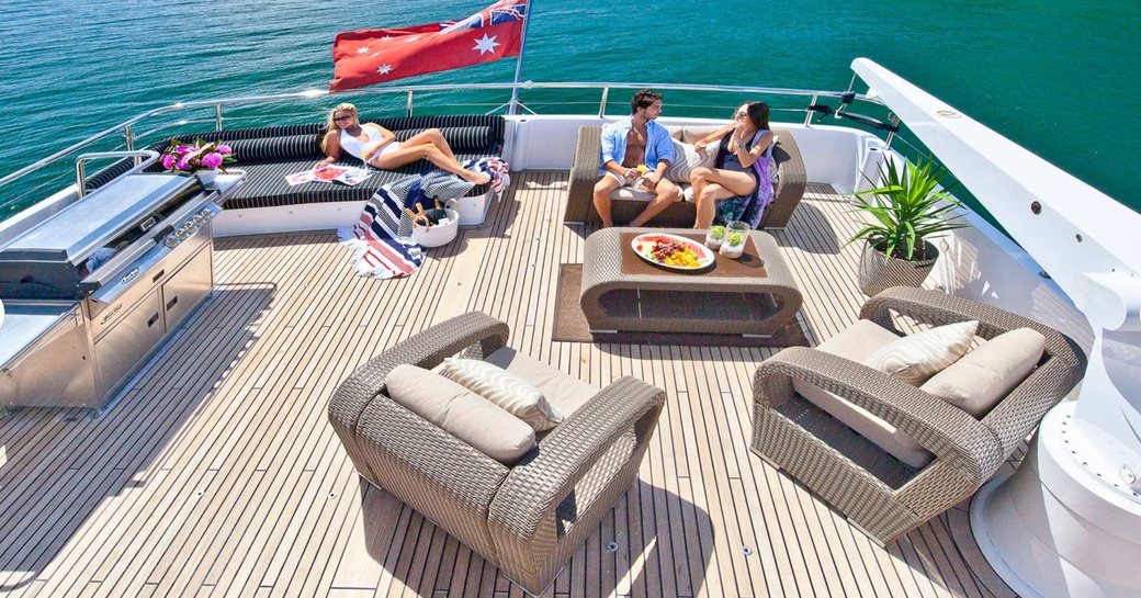 Guests relax on seats and loungers on the aft deck of a yacht