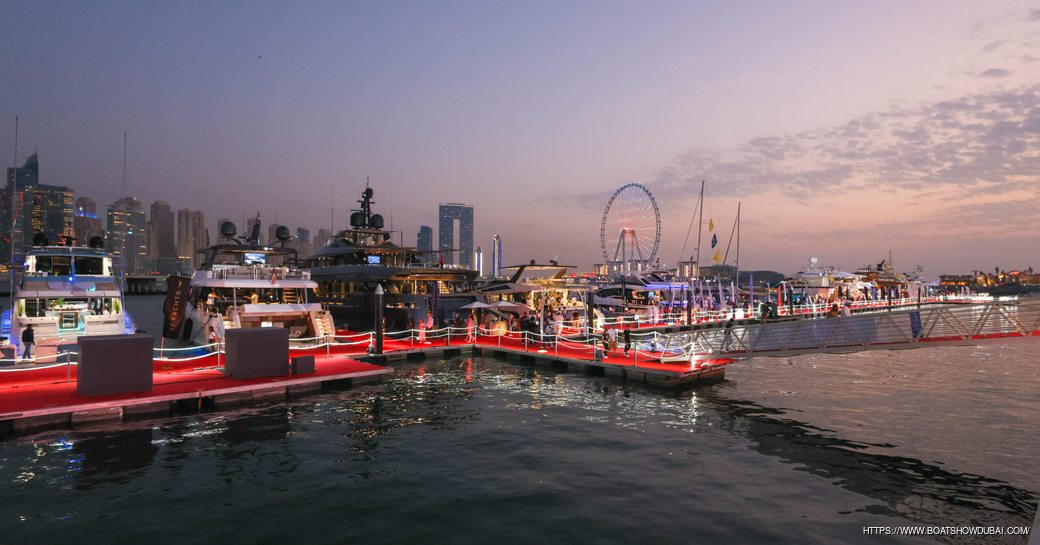 Overview of Dubai International Boat Show at dusk, all lit up with Dubai skyline in the background