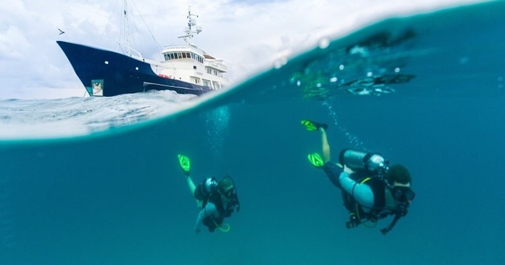 charter guests scuba dive with expedition yacht PIONEER anchored nearby