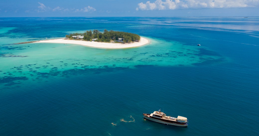 aerial shot of thanda island, with luxury yacht 'over the rainbow' nearby