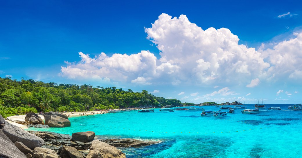 a forest on the left leads to a small beach and turquoise waters in thailand 