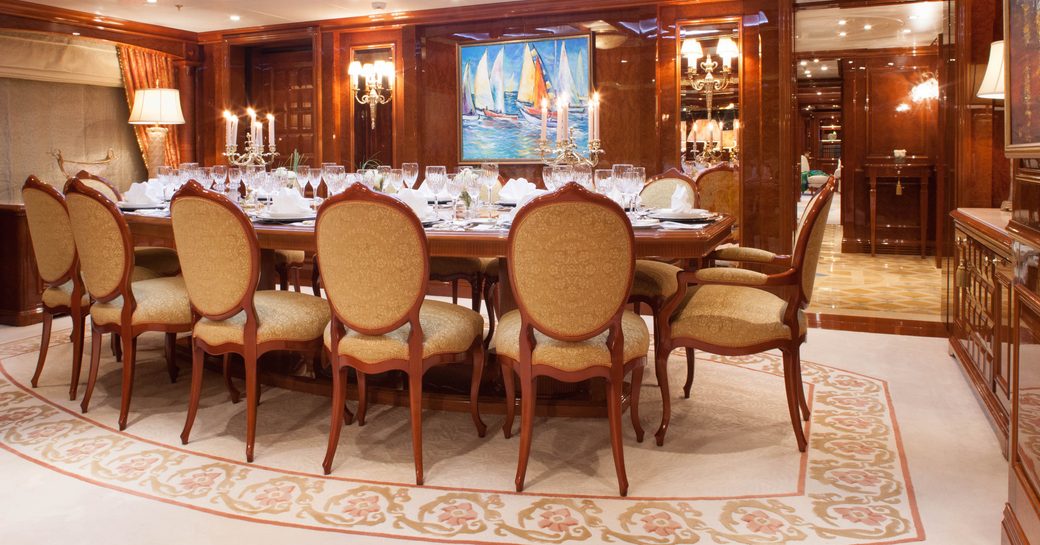 Interior dining area onboard private yacht charter ST DAVID, long table with cream upholstered chairs
