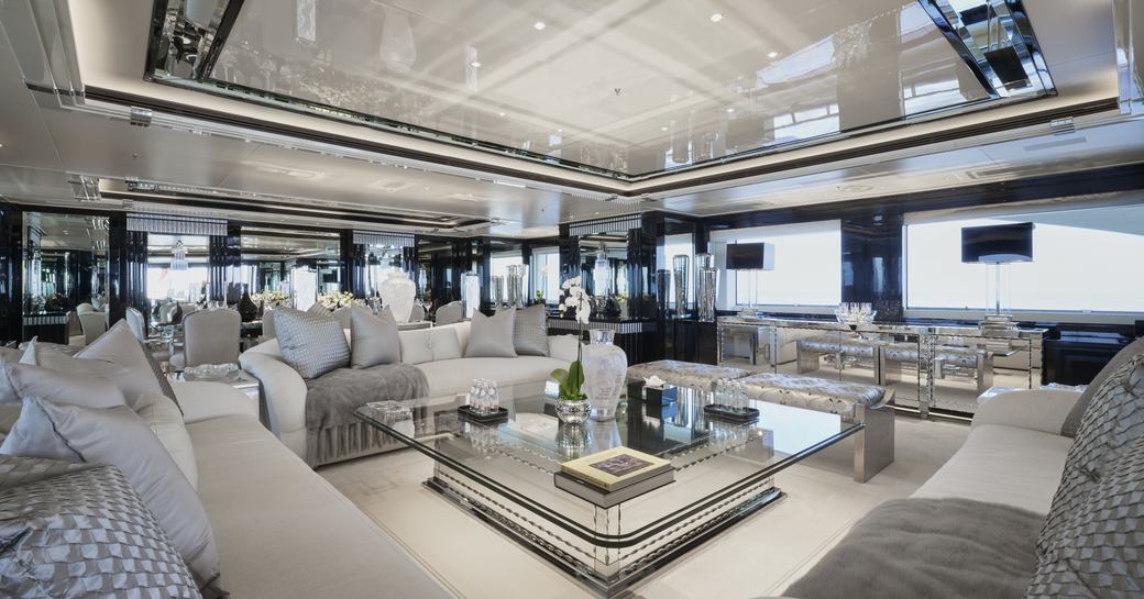Overview of the main salon onboard charter yacht Silver Angel, monochrome lounge area surrounded by wide reaching windows