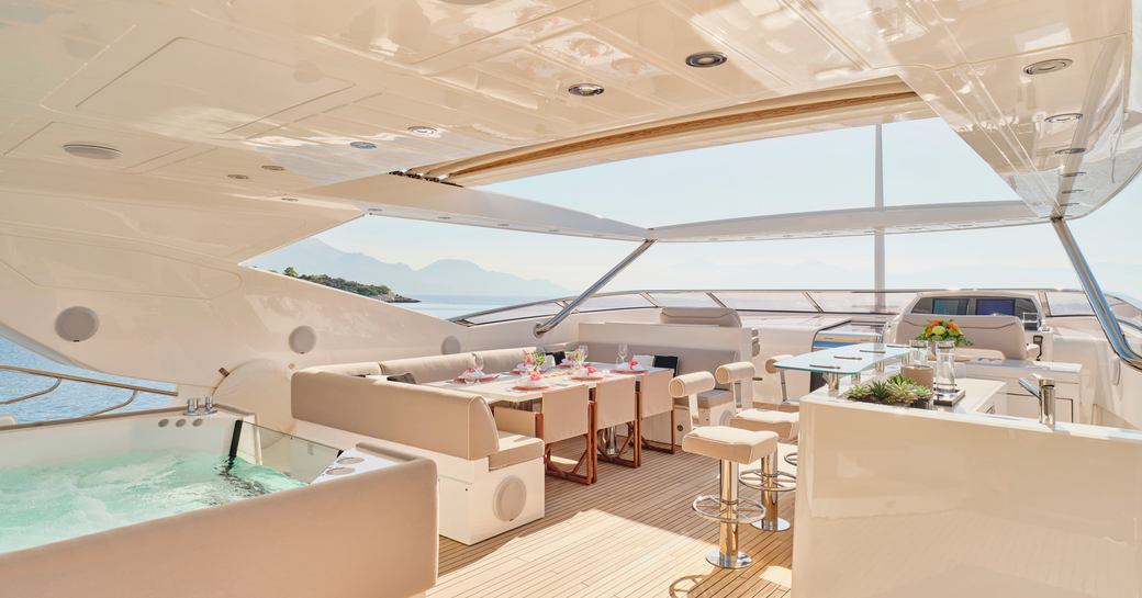 Overview of the flybridge onboard charter yacht MAKANI II, deck Jacuzzi in the foreground with alfresco dining in the background