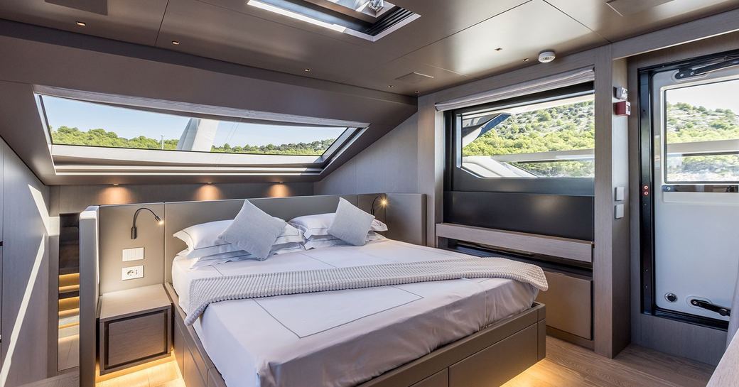 Master cabin onboard charter yacht JICJ, central berth facing forward surrounded by windows and access to exterior deck