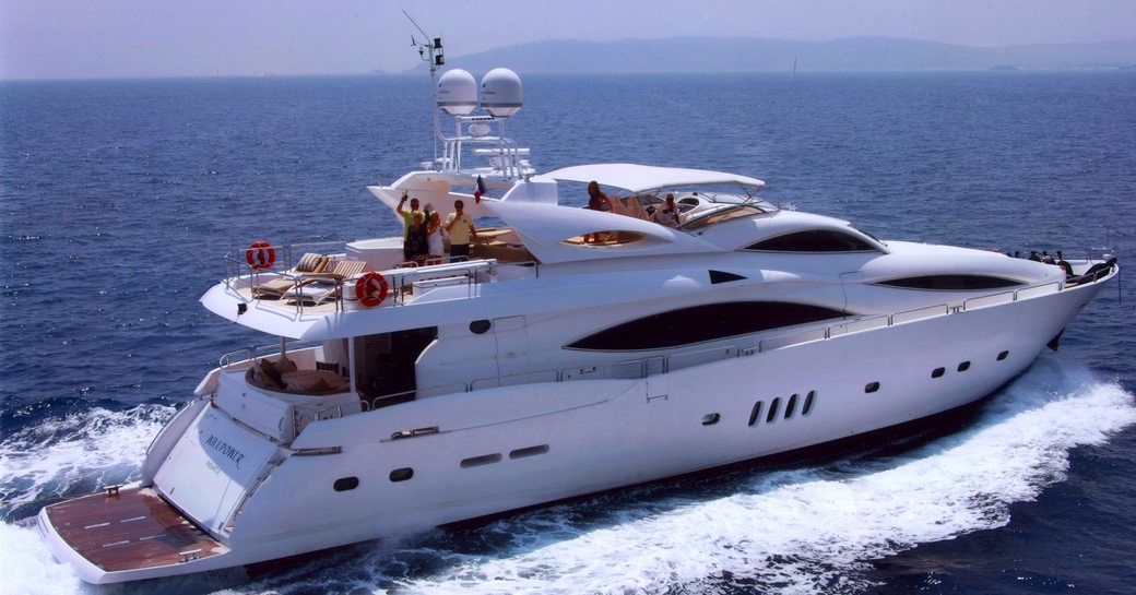 Luxury yacht Mi Alma underway, with people waving on the sundeck