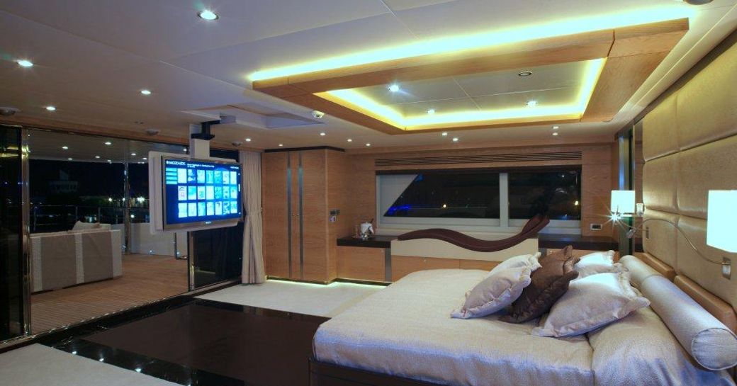 Master cabin onboard charter yacht TATIANA I, central berth facing a large screen with a wide window adjacent