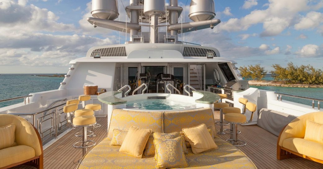 Motor yacht My Seanna sun deck with jacuzzi surrounded by yellow bar stalls and yellow sun pads