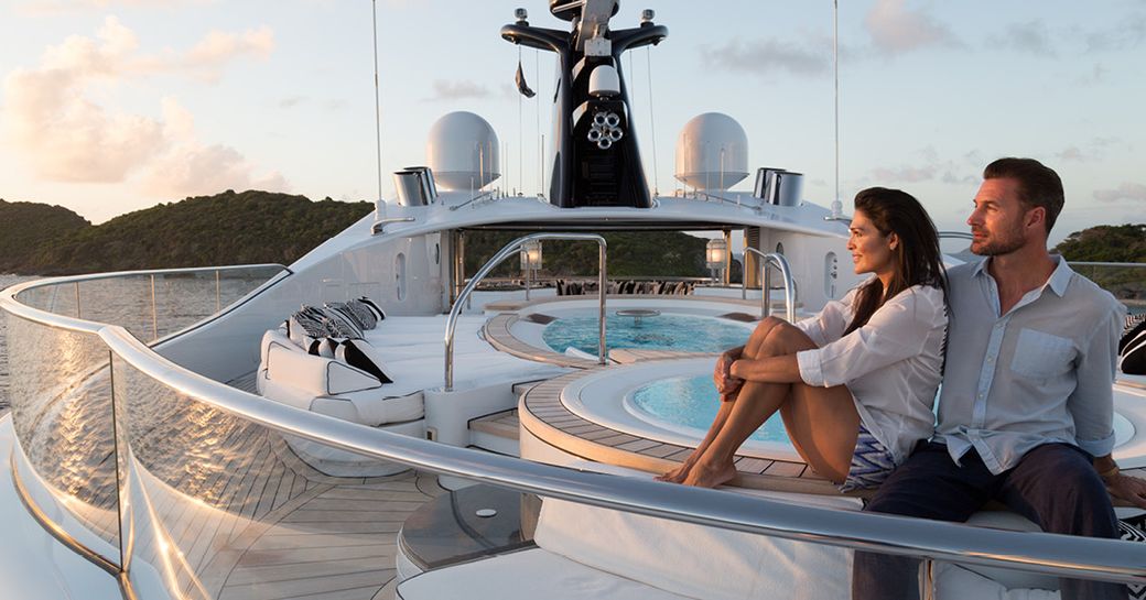two charter guests sit by Jacuzzi on the sundeck of motor yacht Phoenix 2