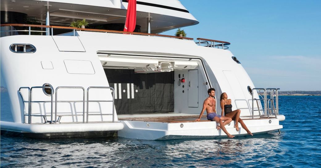 charter guests relax on the drop-down swim platform aboard superyacht 11/11 