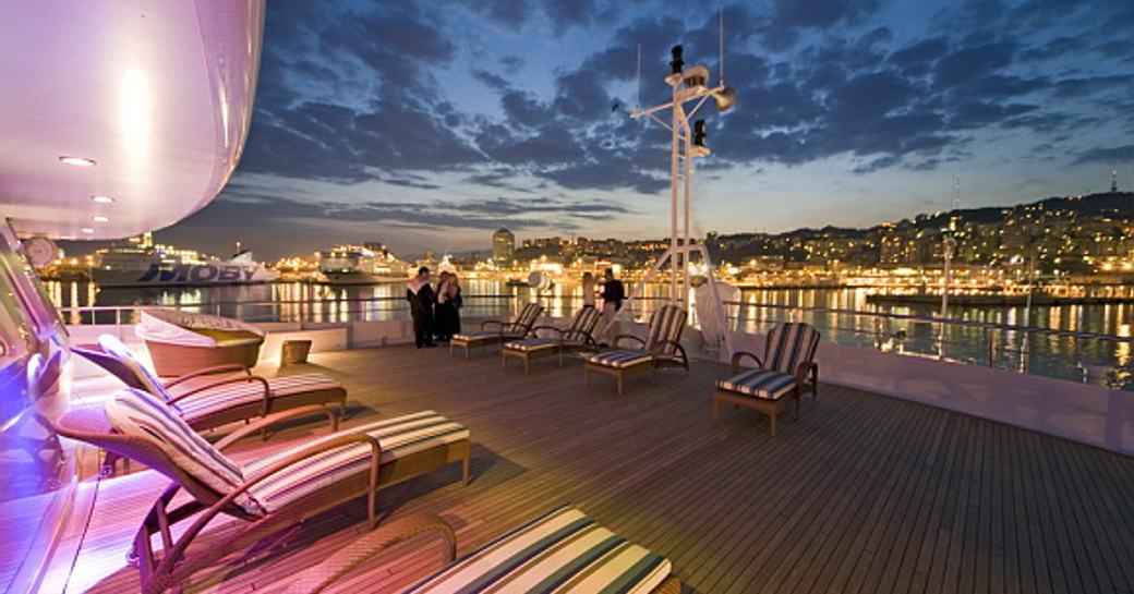 seating area on megayacht lauren l, with harbour lights in distance
