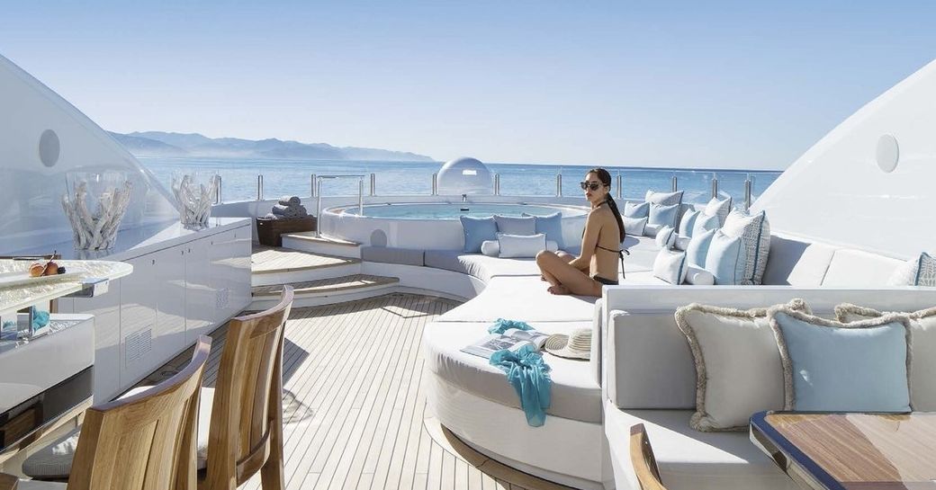 a woman enjoys the sun by lounging on the sunpads of her luxury superyacht 