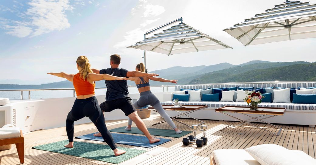 three people doing yoga on luxury charter yacht ADVENTURE