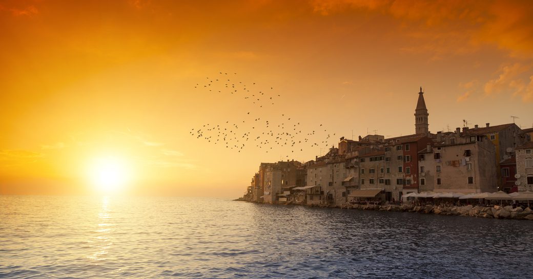 Beautiful sunset over Mediterranean with old buildings on coastline