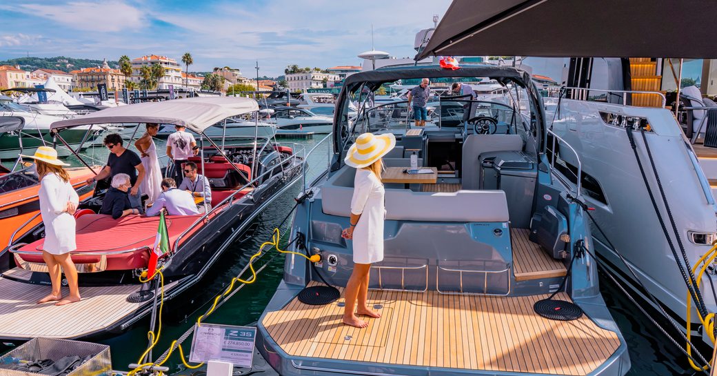 Female representative at the Cannes Yachting Festival looking round an exhibiting motor yacht. Other boats moored alongside.