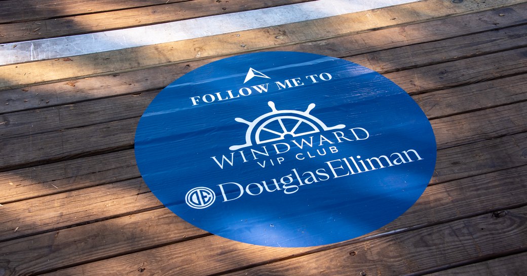 Windward VIP floor sign at FLIBS, blue circle reading "follow me to Windward VIP Club, Douglas Elliman".
