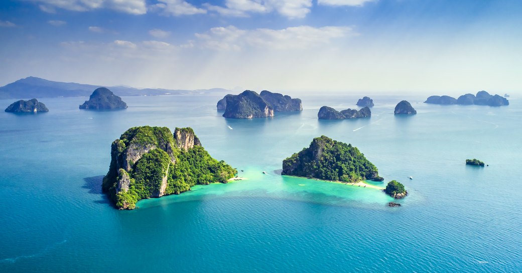 aerial view of islands in phuket in thailand, with blue seas and green foliage covering islands