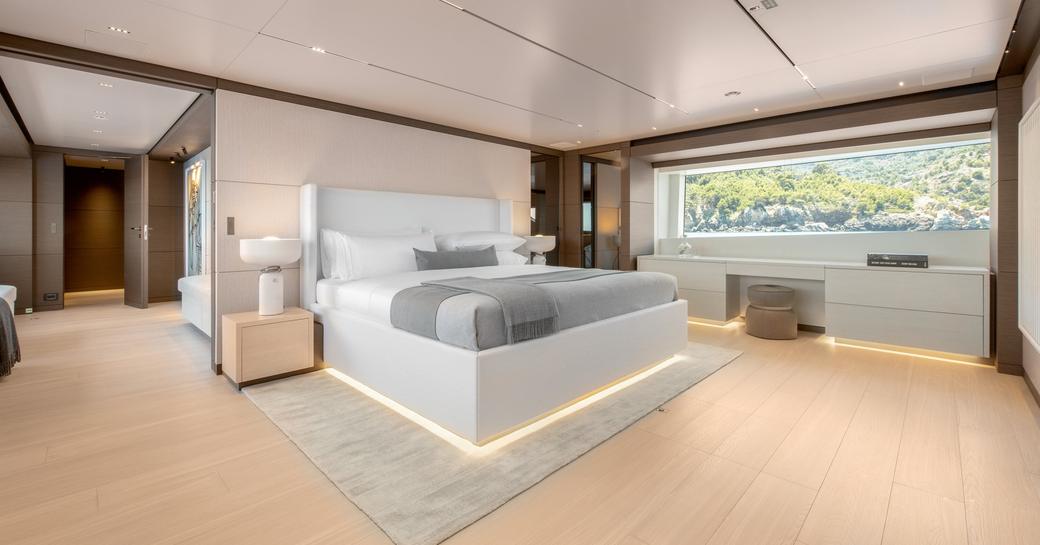 Bedroom on SANGHA superyacht with light colored furnishings, long rectangular window and airy feel