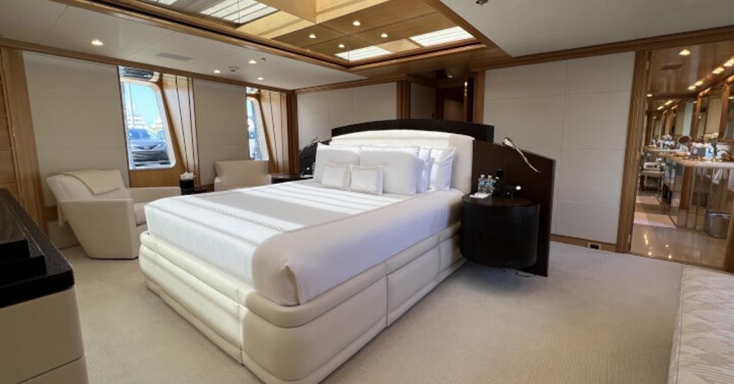 Master cabin onboard charter yacht SPORT, central berth facing forward with dual windows in the background and a small seating area 