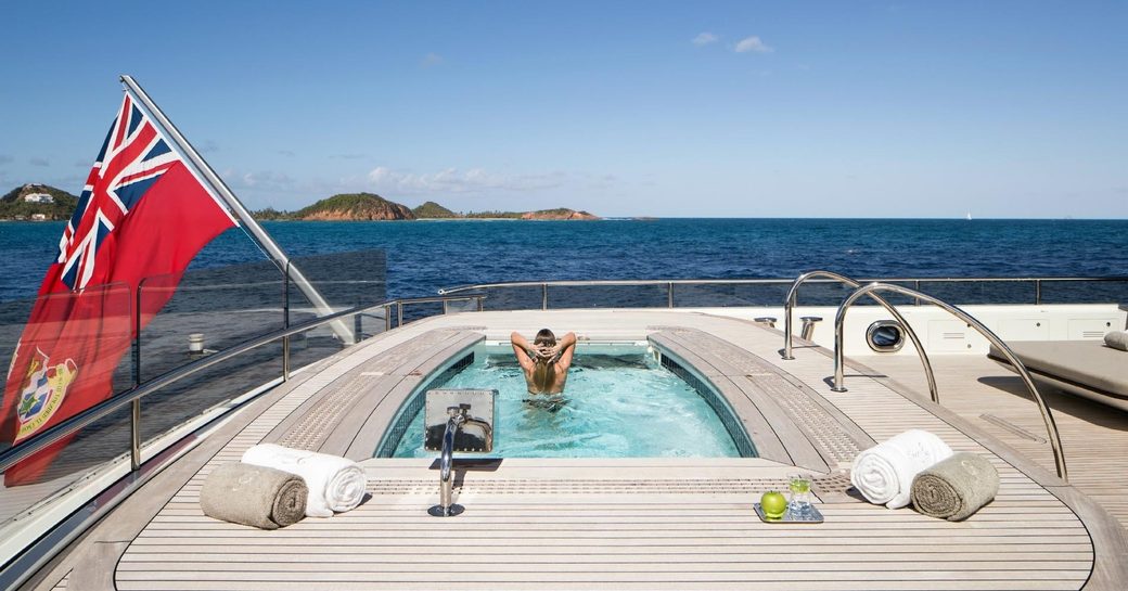 charter guests swims in the pool on the main deck aft of superyacht NAUTILUS