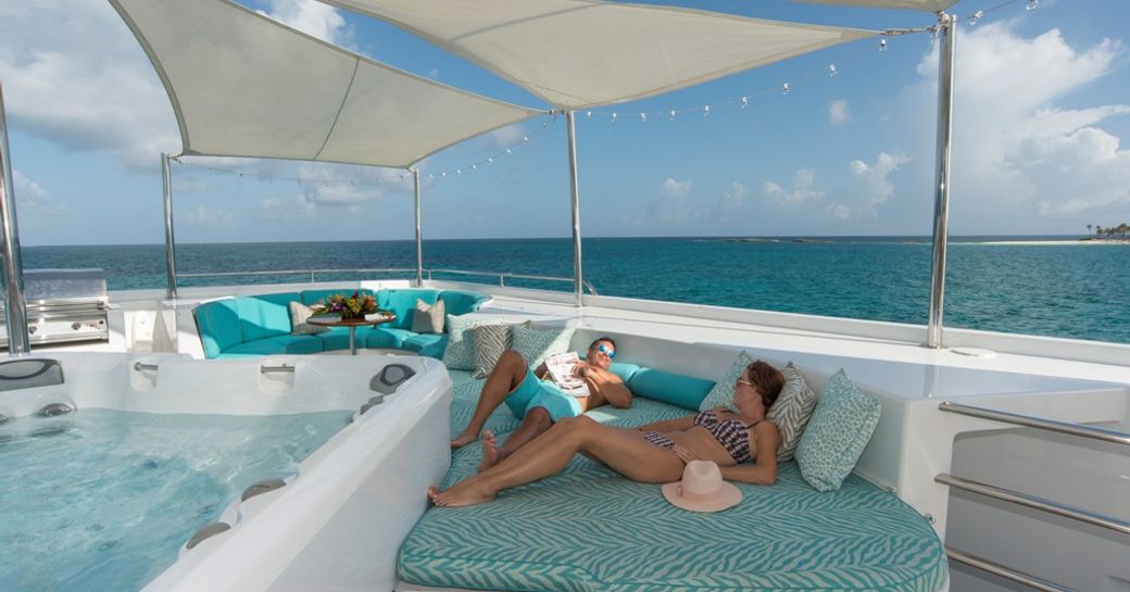 Charter guests relax on luxury yacht RHINO, with blue sunpads and jacuzzi pool