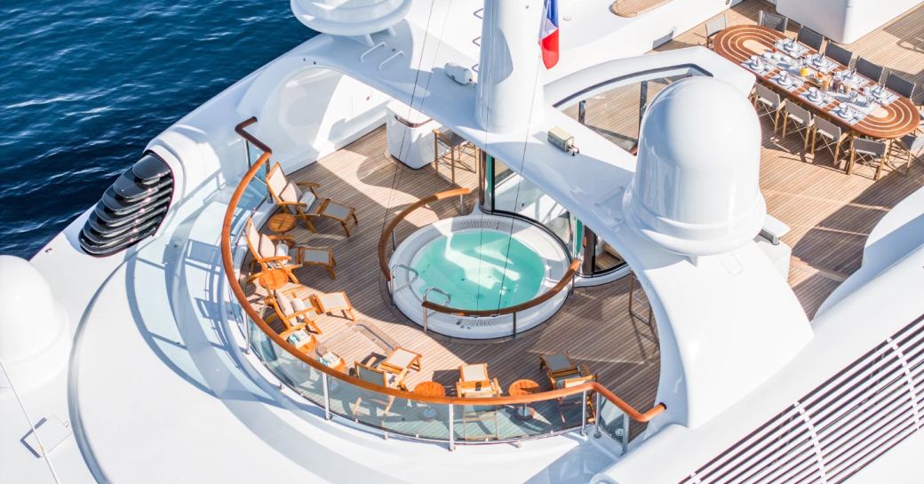Overview of the sun deck onboard charter yacht CARINTHIA VII, deck Jacuzzi surrounded by sun loungers and an alfresco dining option visible