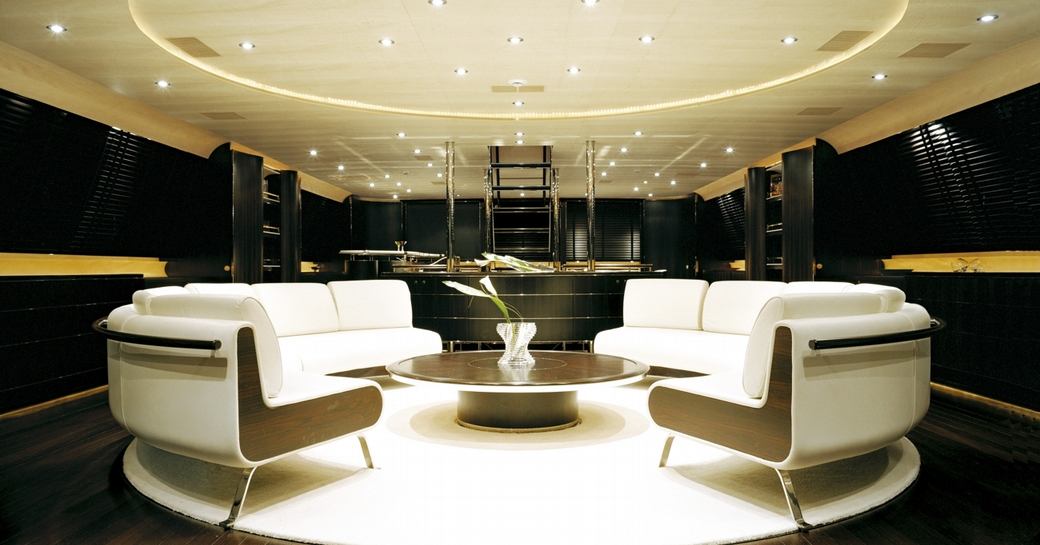 Main salon on luxury sailing yacht, with white cream sofas and dark wood flooring