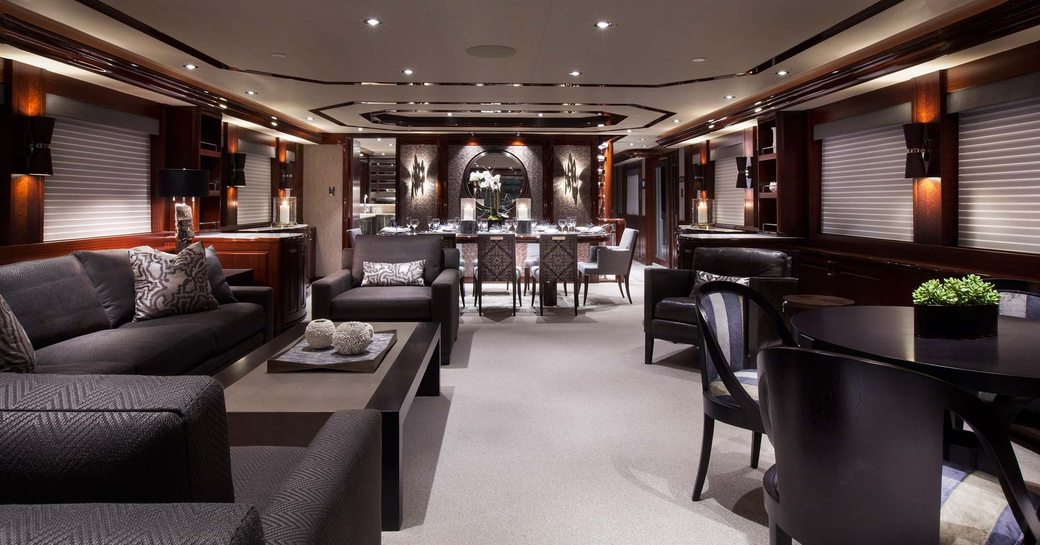 Main salon of superyacht W, with black surfaces and opulent accents and formal dining in background