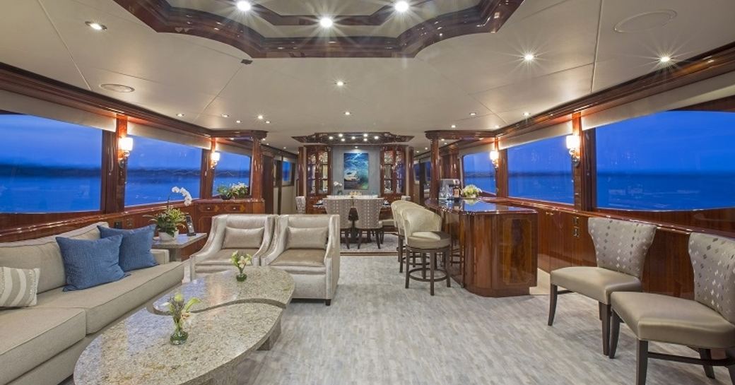 timeless styled main salon with seating area and bar, and dining area beyond on board motor yacht ‘Gale Winds’ 