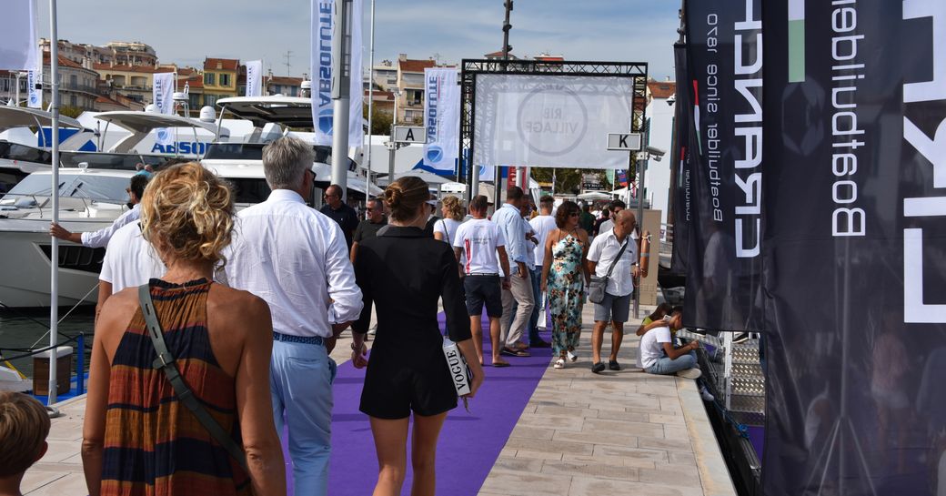 woman walks along the harbour during cannes yachting festival, alongside yachts