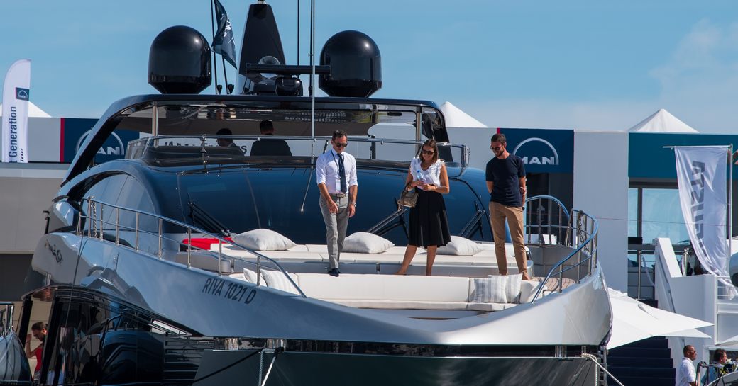 Three people standing on the bow of a motor yacht in discussion at the Cannes Yachting Festival