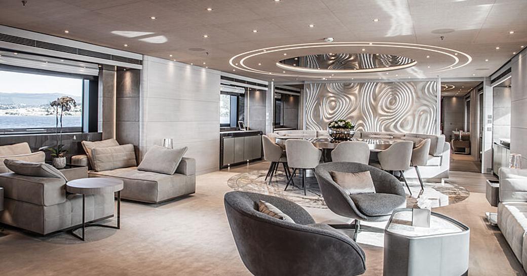 Overview of the main salon onboard charter yacht SEVERIN'S, lounge seating in the foreground, with a dining setup in the background 
