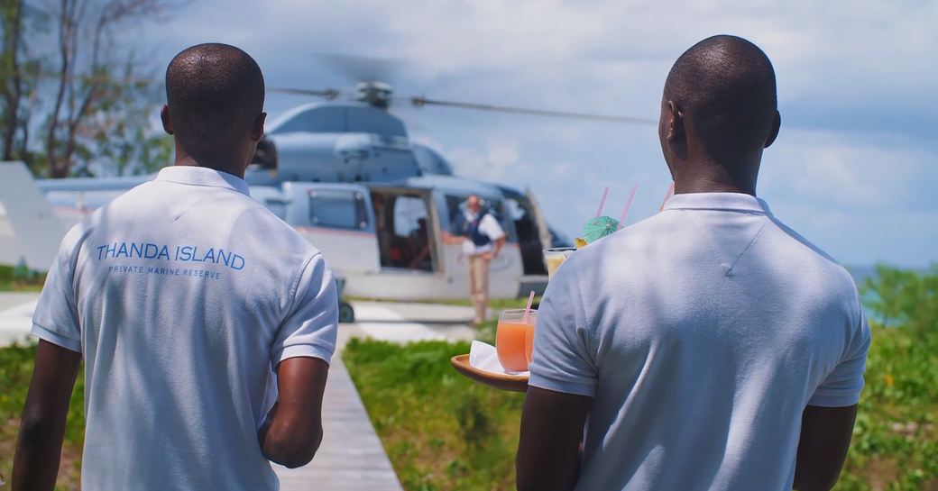 staff wait to give cocktails to guests arriving via helicopter on thanda island