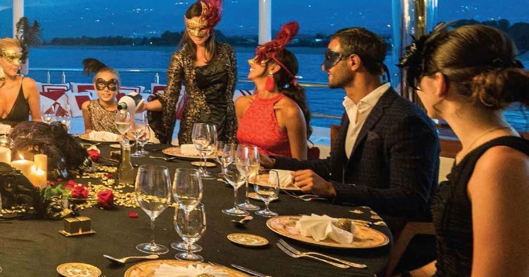 Guests dress up in masks for a themed evening on board a charter yacht