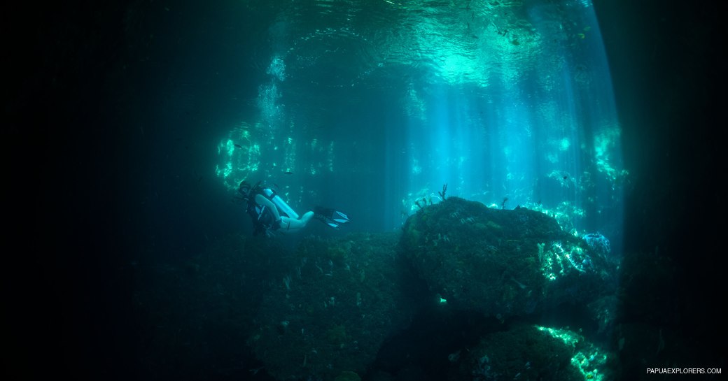 Girl swimming with diving gear on through The Passage's grotto 