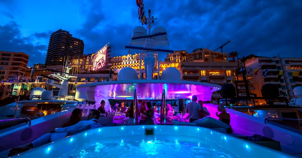 nighttime shot of jacuzzi on a superyacht during a yacht party at the monaco grand prix, with buildings of monte carlo in background